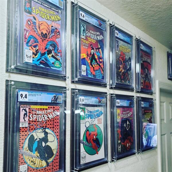 User-generated photo (UGC) of a room showcasing the Crafti Comics UV-FLEX Display Case, a frame designed for graded comic books. This frame features 99% UV-protection with museum-quality acrylic as standard. It can be hung in portrait or landscape orientation using twin engraved mounting holes. Crafti's laser-cut layered designs add depth without applying excessive pressure. In this photo are all Spiderman comic books.